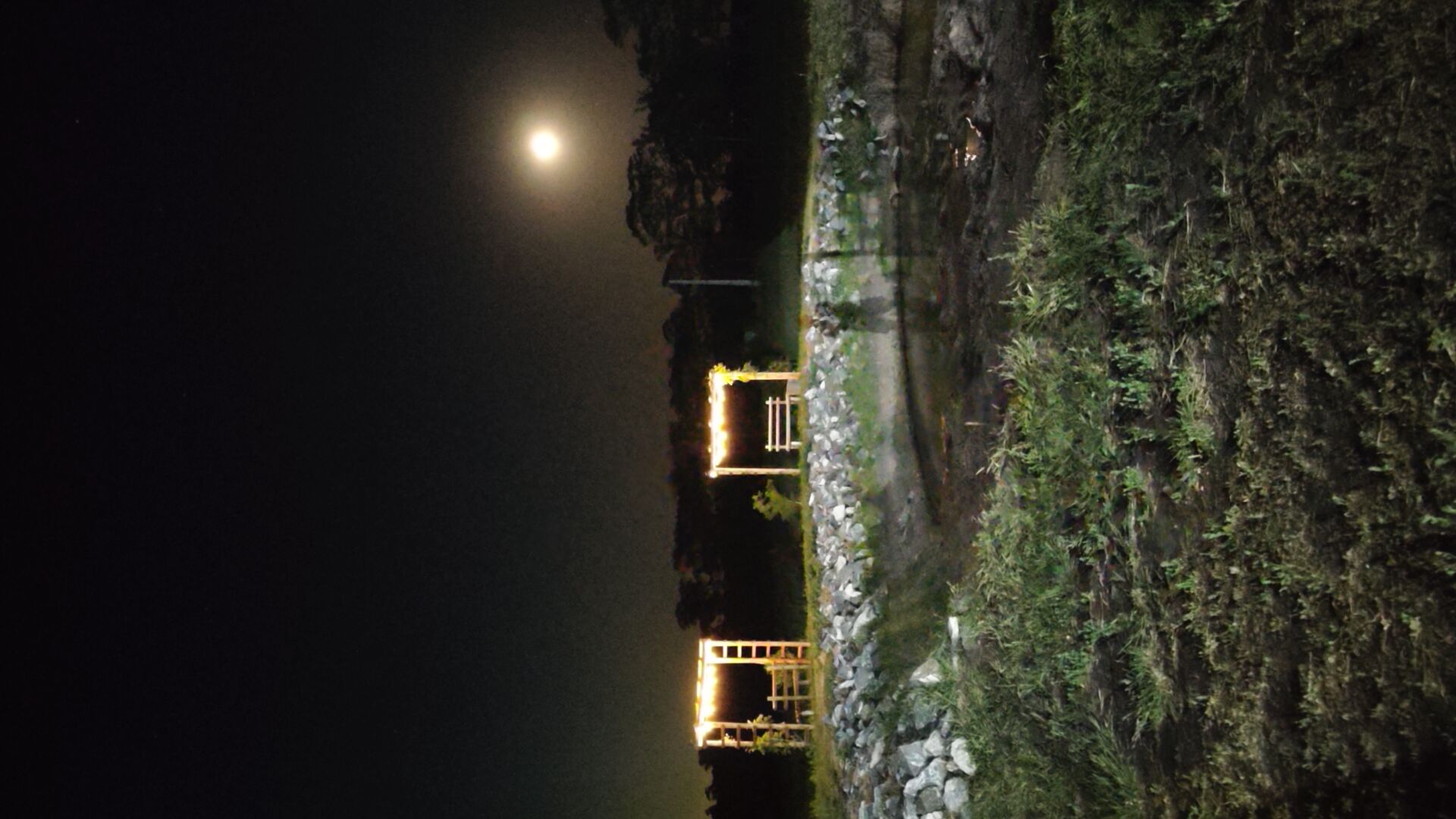 Cabinas iluminadas junto al agua bajo la luna