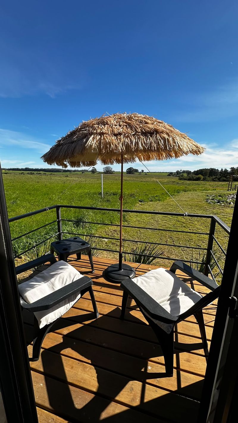 Terraza privada de la unidad Las Glicinas, con sombrilla y vista al campo